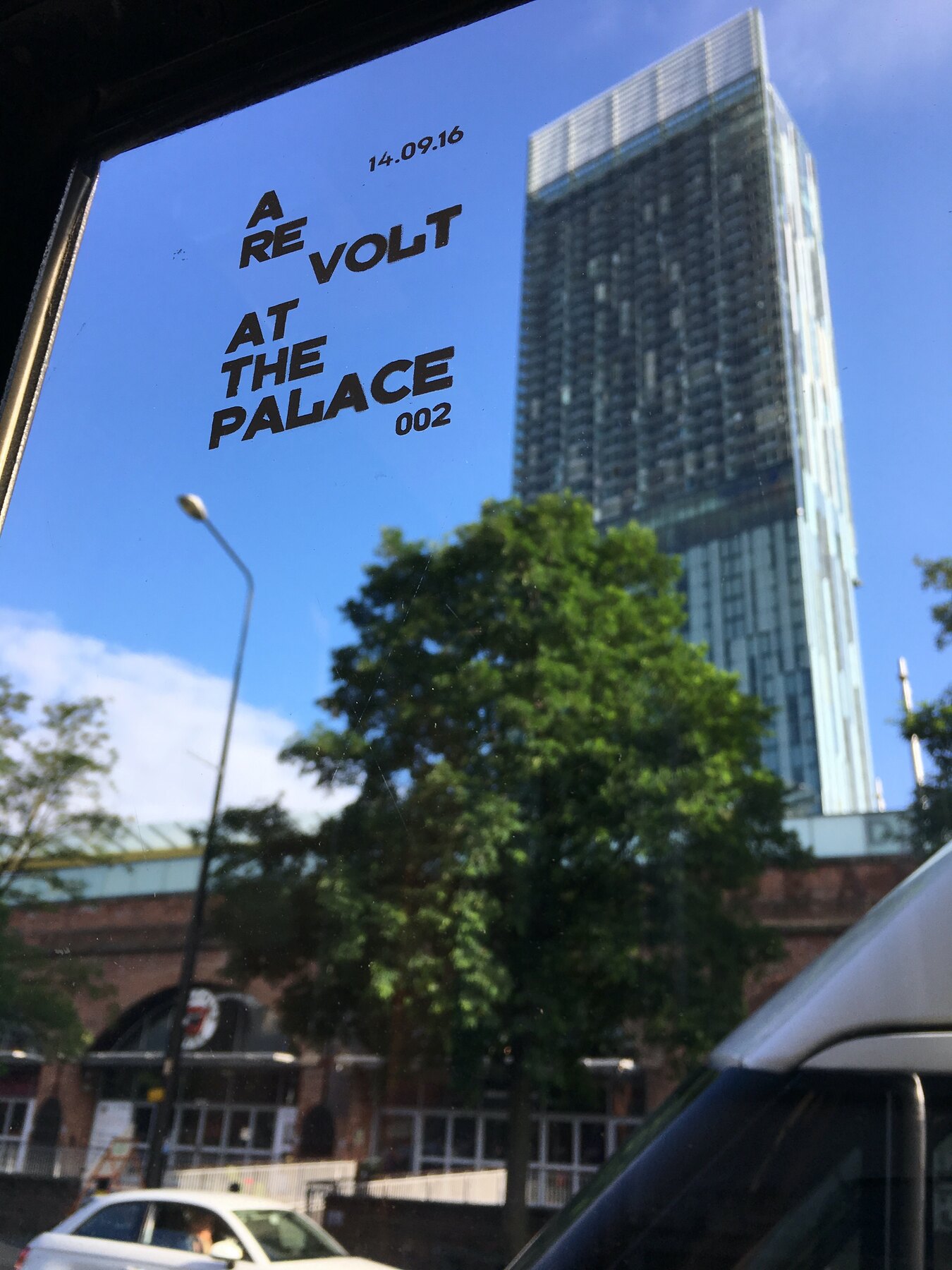 A Re Volt at the Palace printed in white ink on glass, with Beetham Tower behind