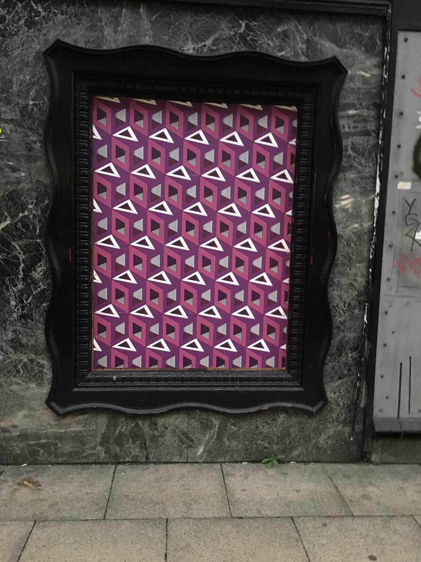 Purple wallpaper pasted inside an ornate carved frame on a Northern Quarter shopfront