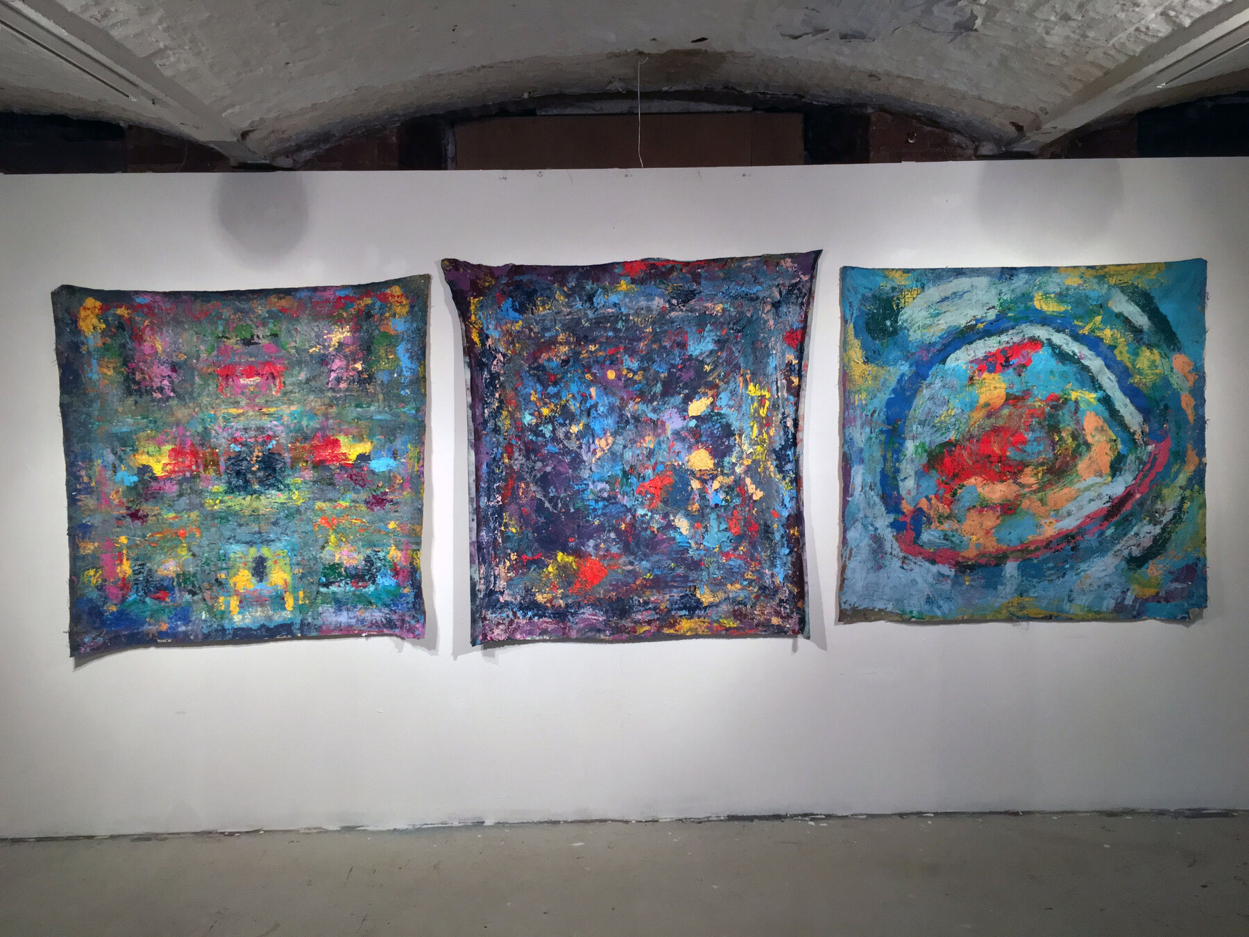 Three unstretched fabric rubbings pinned to a studio wall, taken from the surface of the paintings
