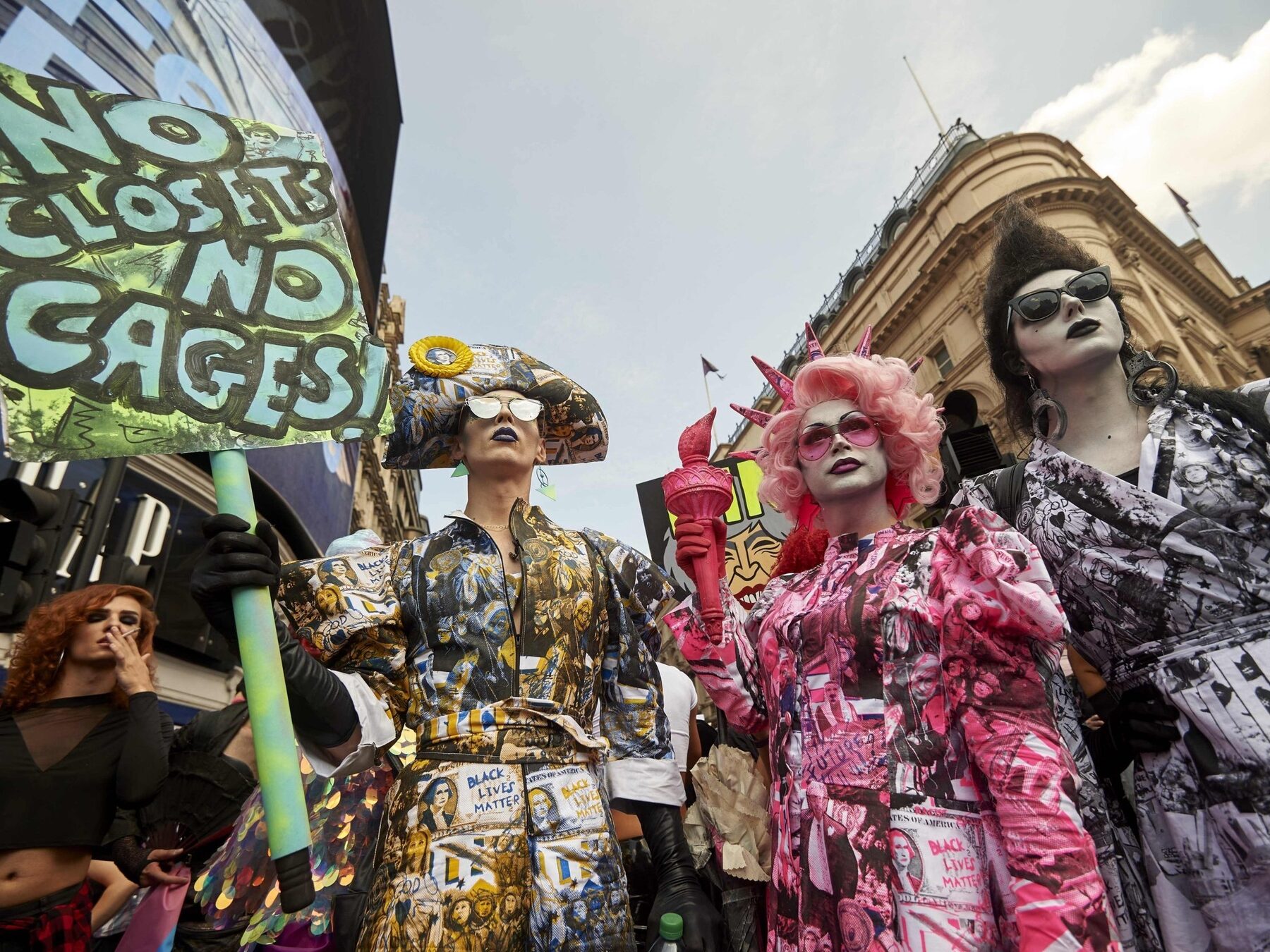 The three Drag Against Trump performers at Piccadilly Circus, London, holding a No Closets No Cages placard