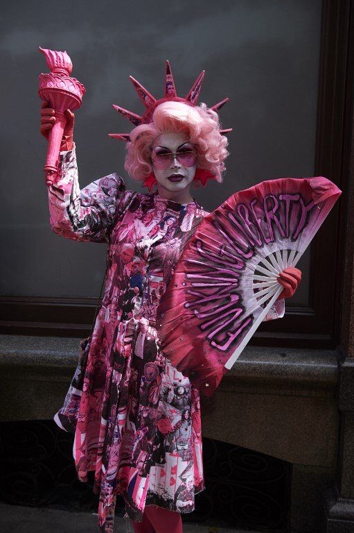 A performer dressed as a pink Statue of Liberty in printed fabric designed by Mark Jermyn for Drag Against Trump