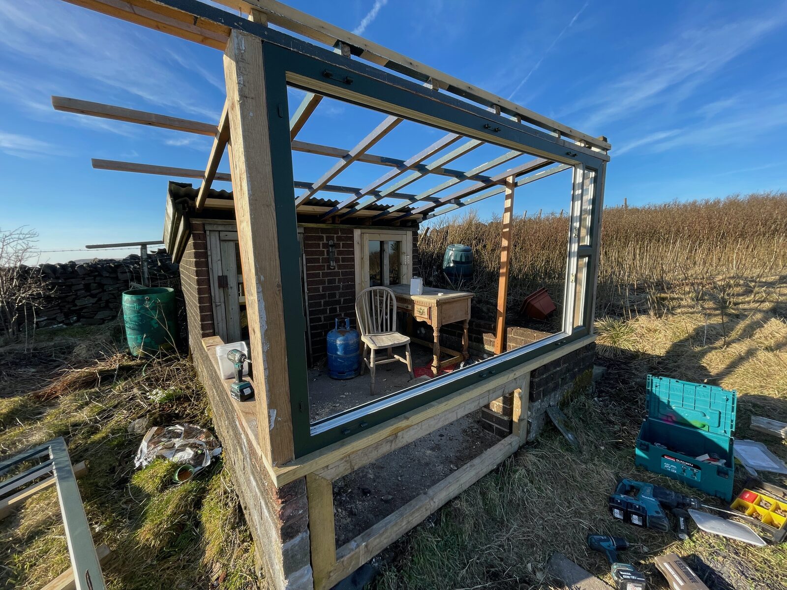 A greenhouse built from the recycled window panels, up on the hillside.