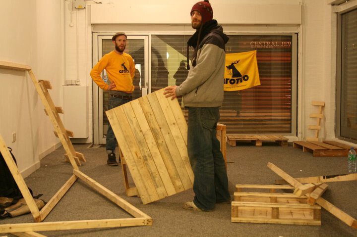 Building shop shelving and display units from pallet wood ahead of opening, with the Grotto flag in the background