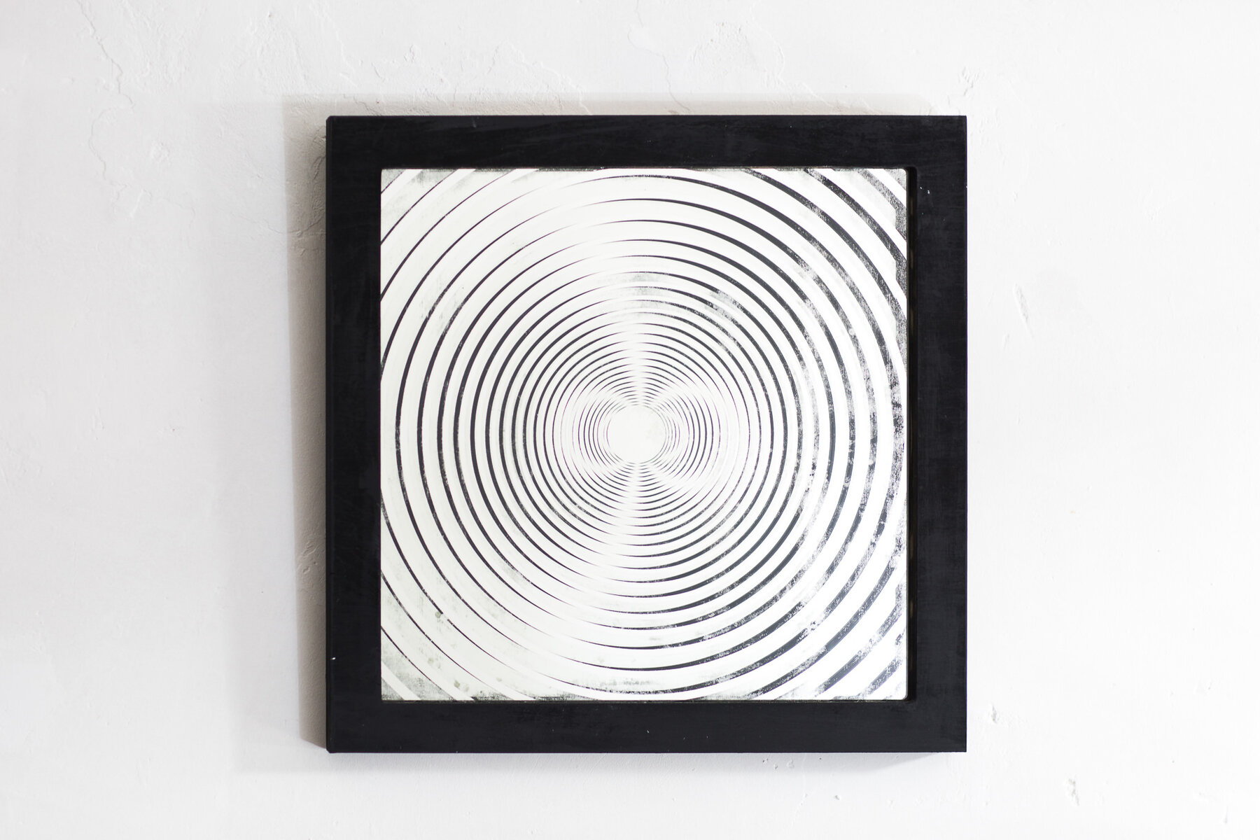 A framed mirror with a bold, high-contrast concentric ring pattern