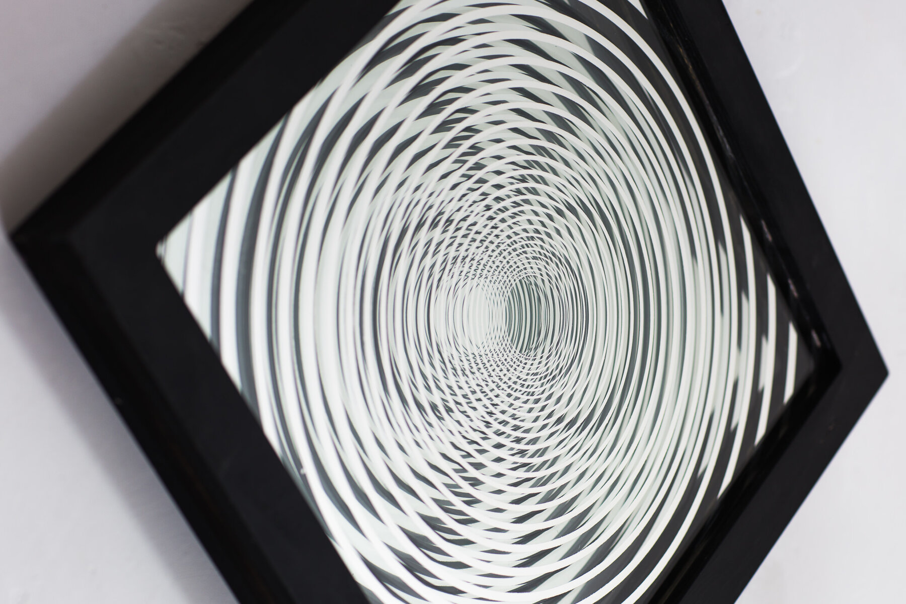 Detail of a laser-etched mirror at an angle, showing its dimensional, tunnel-like pattern
