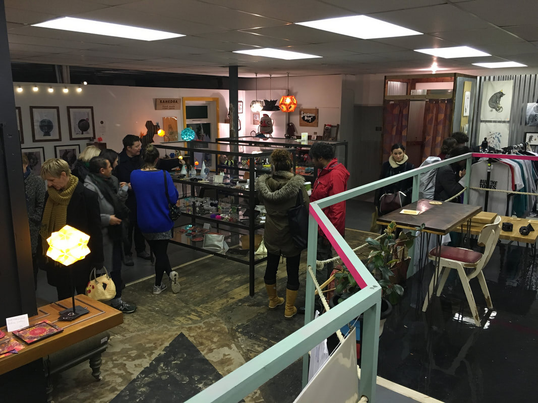 Visitors browsing the shop interior among shelving, lighting and handmade goods