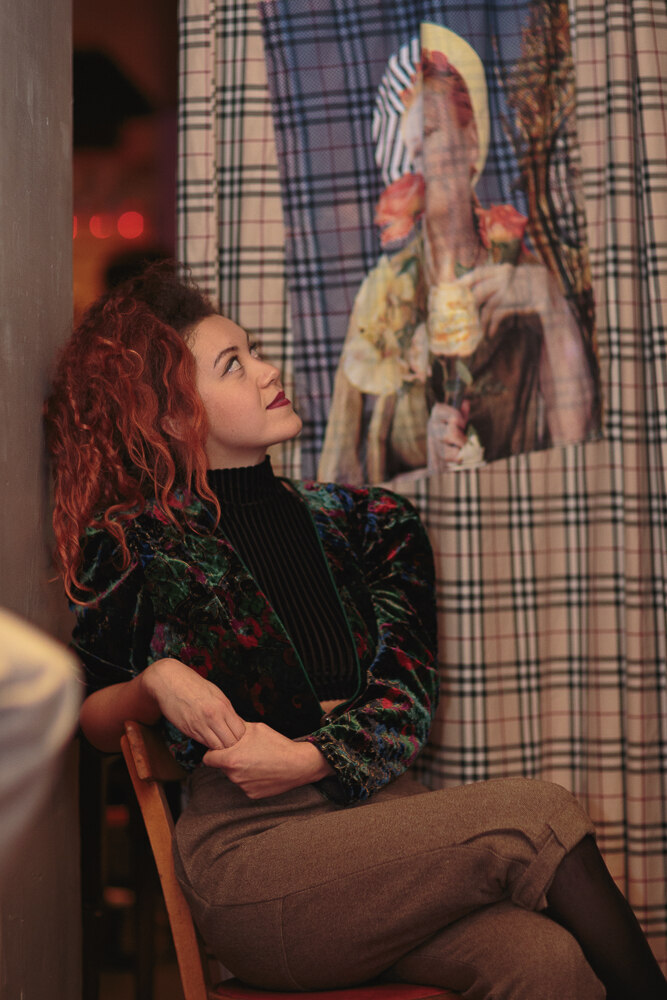 A guest looking up at an exhibited print through a curtain doorway