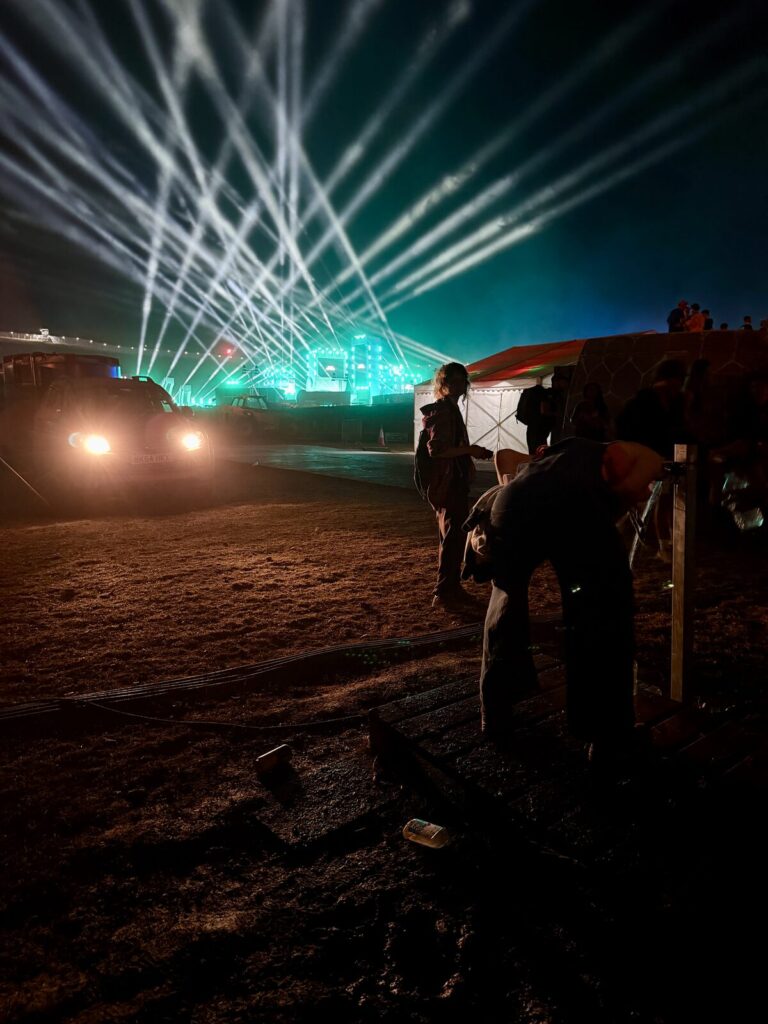 Lasers over the crowd on the closing night at Boomtown, seen from above the back of the field